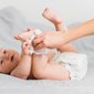 Imagem de uma mãe limpando o pé de um bebê com fralda trocada, simbolizando a importância do kit higiene.