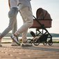 Pais caminham à beira da praia empurrando carrinho, ilustrando itens para passeio com o bebê