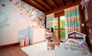 Mãe abraçando filha em quarto decorado, ilustrando inspirações de cores para quarto de bebê