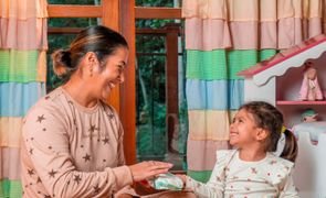 Mãe e filha no quarto, organizando itens essenciais para bebê com caixa organizadora e decoração acolhedora
